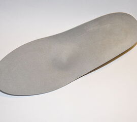 Einlage zur Behandlung der plantaren Fasciitis. Erkennbar ist die Fersenfassung und die nach distal gezogene Hohllegung der Plantarfaszie.